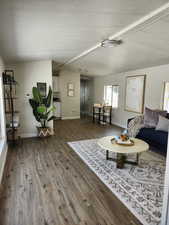 Living room with dark wood-style floors, a textured ceiling, and vaulted ceiling