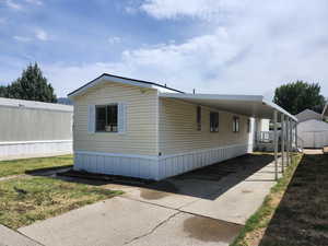 View of side of home featuring a shed, an attached carport, concrete driveway, and a yard