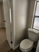 Bathroom with a textured wall and dark wood-style flooring