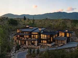Back of house at dusk with curved driveway, a chimney, an attached garage, and a standing seam roof