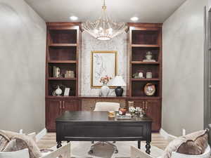 Builders Model for example purposes only. Office area with built in shelves, light wood-style floors, and a chandelier