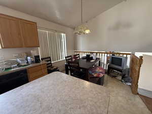 Kitchen with lofted ceiling, light countertops, hanging light fixtures, a chandelier, and black dishwasher