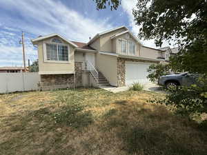 View of front of home with stone siding, stucco siding, a garage, and concrete driveway