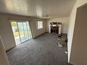 Unfurnished living room with a glass covered fireplace, carpet, and a textured ceiling