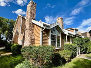 View of home's exterior with a chimney and a lawn