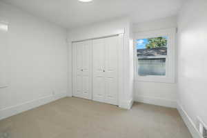 Unfurnished bedroom with light carpet and a closet