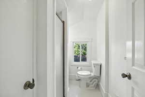 Full bath featuring vaulted ceiling, tile patterned flooring, and a shower stall