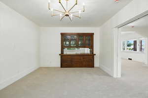 Unfurnished dining area featuring light colored carpet and a chandelier