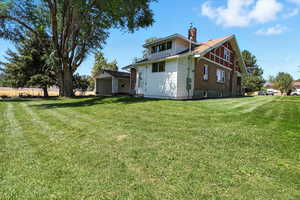 Back of house with a chimney and a lawn