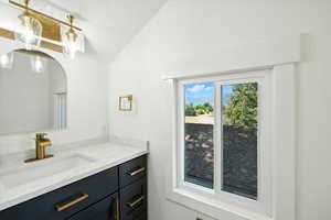 Bathroom with vanity and lofted ceiling