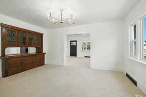 Unfurnished dining area with light carpet and a chandelier