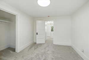 Unfurnished bedroom with light carpet, a chandelier, and a closet