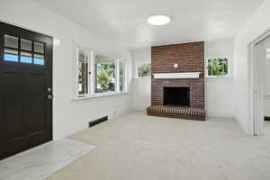 Unfurnished living room with carpet floors and a brick fireplace