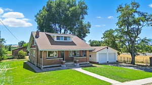 View of front of property featuring brick siding, roof with shingles, a detached garage, and driveway