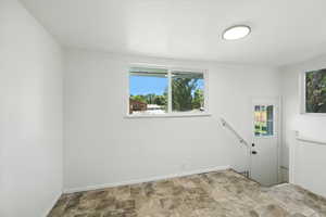 Unfurnished room featuring stone finish floors and baseboards
