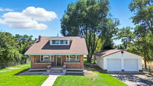 View of front of home featuring a detached garage, an outdoor structure, brick siding, a shingled roof, and a chimney