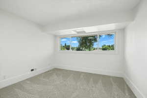Carpeted spare room featuring baseboards