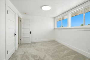 Spare room featuring light carpet and a textured ceiling