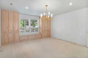 Unfurnished dining area featuring a chandelier, light colored carpet, and recessed lighting