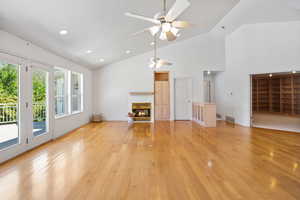 Unfurnished living room featuring light wood-style floors, high vaulted ceiling, a tile fireplace, recessed lighting, and a ceiling fan