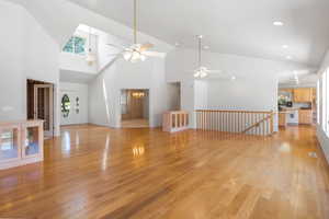 Unfurnished living room with high vaulted ceiling, light wood-style flooring, healthy amount of natural light, a ceiling fan, and recessed lighting