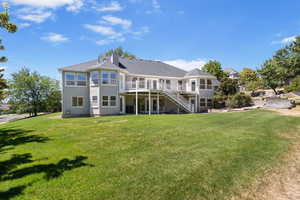 Back of property featuring a patio, stairway, a deck, and a lawn
