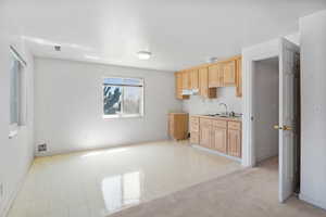 Kitchen featuring light brown cabinetry, light countertops, and under cabinet range hood