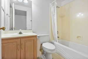 Bathroom featuring shower / tub combo with curtain, light tile patterned floors, and vanity