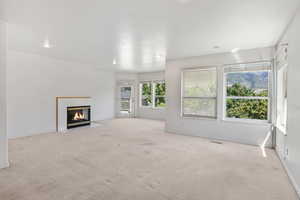 Unfurnished living room featuring a tile fireplace, light carpet, and recessed lighting