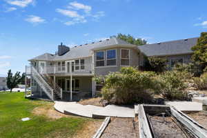 Rear view of property featuring a patio area, stairs, a shingled roof, a lawn, and a deck