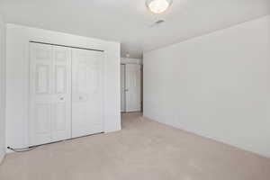 Unfurnished bedroom featuring light carpet and a closet