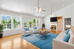 Living room with a fireplace, light wood finished floors, recessed lighting, high vaulted ceiling, and ceiling fan