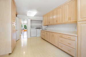 Kitchen featuring light brown cabinets, light countertops, light flooring, and washer and clothes dryer