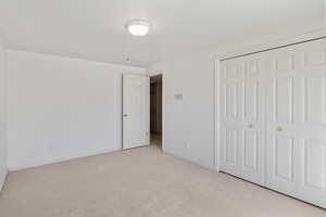 Unfurnished bedroom with light colored carpet and a closet