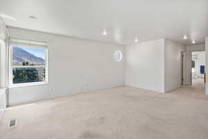 Unfurnished room with light colored carpet, a mountain view, and recessed lighting