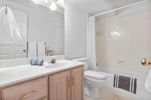 Full bathroom with shower / bathtub combination with curtain, vanity, and light tile patterned floors