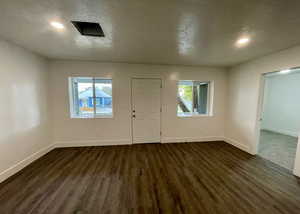 Foyer entrance with a textured ceiling and dark wood-style floors