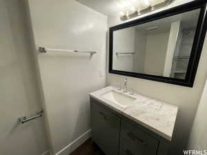 Full bath with vanity, a textured ceiling, and a shower