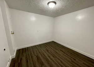 Empty room featuring dark wood finished floors and a textured ceiling