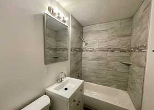 Full bathroom with shower / tub combination, vanity, and a textured ceiling