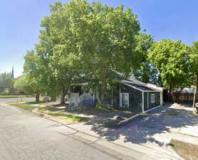 View of property hidden behind natural elements with concrete driveway