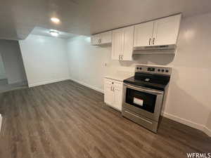 Kitchen with white cabinetry, electric stove, light countertops, dark wood-style floors, and a textured ceiling