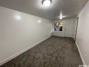 Unfurnished room with dark carpet and a textured ceiling