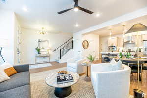 Living room with stairs, recessed lighting, a chandelier, light wood-style floors, and a ceiling fan
