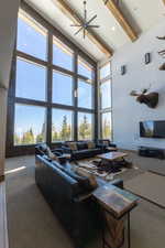 Living area featuring a towering ceiling, carpet flooring, beamed ceiling, a ceiling fan, and recessed lighting