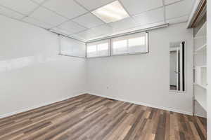 Unfurnished room with dark wood-style flooring, wooden walls, and a paneled ceiling