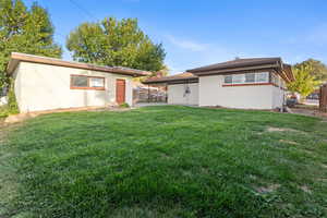 Back of house with a lawn and brick siding