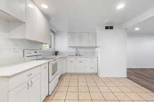 Kitchen featuring white electric range oven, white cabinets, light countertops, light tile patterned flooring, and recessed lighting