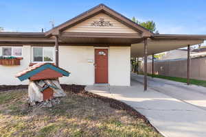 Entrance to property with an attached carport, driveway, and brick siding