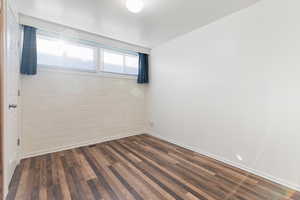 Spare room featuring dark wood-type flooring and baseboards